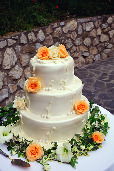 Torta nunziale in un guscio di glassa rifinito con rose e una ghirlanda di edera